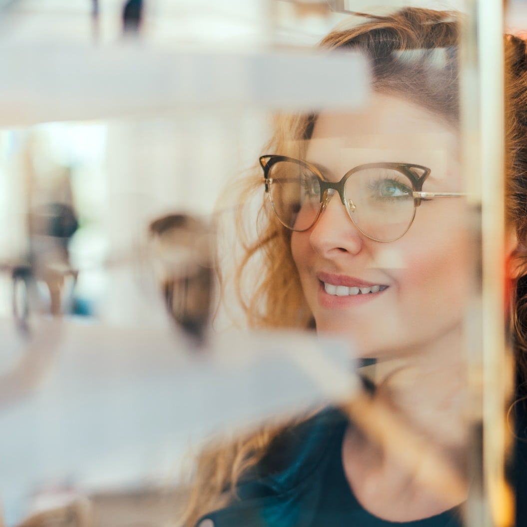 Junge Frau mit Brille schaut sich neue Brillen an